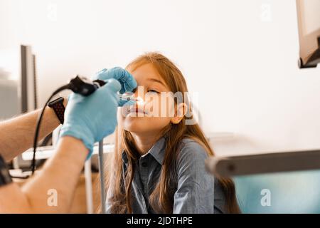 Nose endoscopy of child. Rhinoscopy procedure with rhinoscope. ENT doctor otolaryngologist with headlight treat nose kid patient Stock Photo