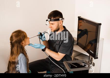 Nose endoscopy of child. Rhinoscopy procedure with rhinoscope. ENT doctor otolaryngologist with headlight treat nose kid patient Stock Photo