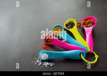 https://l450v.alamy.com/450v/2jdtke8/closeup-multicolored-measuring-spoons-with-spices-chili-flakes-a-mix-of-pepper-peas-curry-paprika-and-coarse-sea-salt-black-chalk-board-backgroun-2jdtke8.jpg