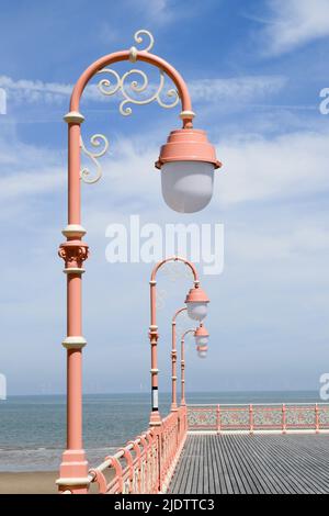 Ornate, pink victorian lampposts against a deep blue sky Stock Photo
