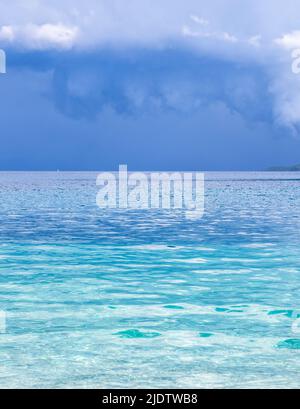 Turquoise sea against dark grey clouds with boat on the horizon at Mikros Gialos on the Ionian island of Lefkada Stock Photo