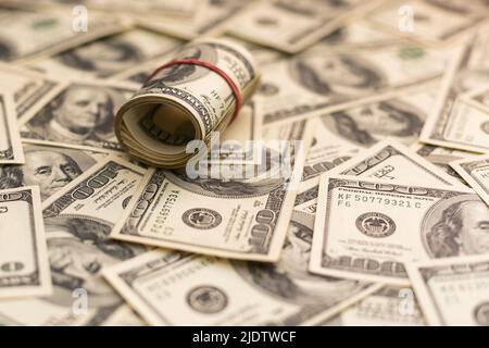 A roll of money tightened by an elastic band close-up macro shot. Usd money wad, bundle of usa cash. Several American dollar bills rolled and tied up Stock Photo