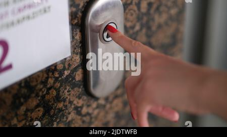 Female finger with red manicure pressing elevator button closeup Stock Photo