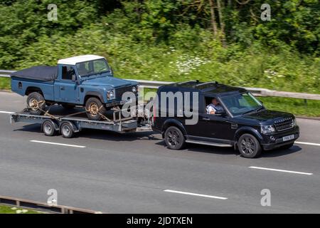 2016 black Land Rover Discovery SDV8 Graphite, towing 1997 90s nineties LWB blue Land Rover 2dr Diesel 5 speed manual pick up; driving on the M61 Motorway, Manchester, UK Stock Photo