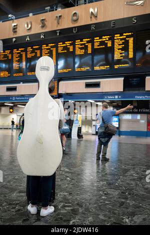 On the second day of the UK's rail strike, when railway and London Underground workers with the RMT union have taken industrial action, the most disruptive rail strike across England, Scotland and Wales for thirty years, cellist Jane Lindsay nervously waits for the last train to Glasgow from Euston station, hopefully in time for an evening performance, on 23rd June 2022, in London, England. After an earlier cancelled train and then a cancelled EasyJet flight, Jane tries for the third time to reach her concert venue. Her train is scheduled to arrive with less than an hour before the 'Don Giovan Stock Photo