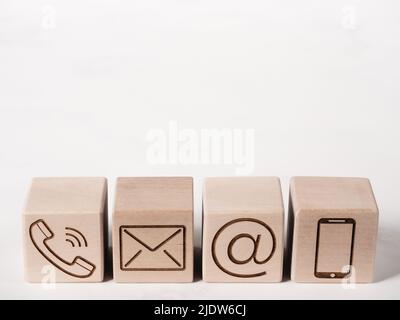 Wood blocks with symbols phone, mail, and address as contact us concept Stock Photo