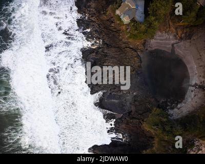 Shooting from a drone. View of the ocean with foamy white waves, a rocky shore overgrown with moss. Storm in the ocean. Ecology, geology, environmenta Stock Photo