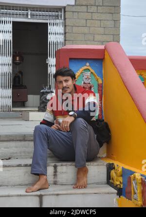 Photo of a young guy looking at camera while sitting on stairs in Shiva temple Stock Photo