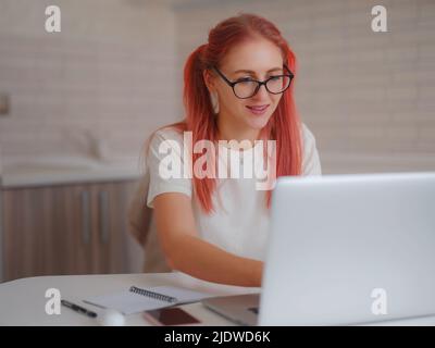 pleasant happy young female freelancer working on computer at home. Attractive woman studying online using laptop software, web surfing information or Stock Photo