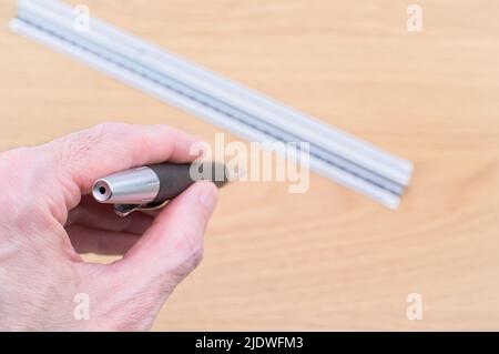 metal decimal ruler with hand holding pencil on a wooden desk background Stock Photo