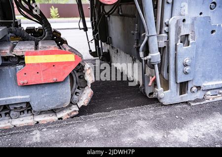 Large Road cold milling machine removes the old asphalt and loading  Stock Photo