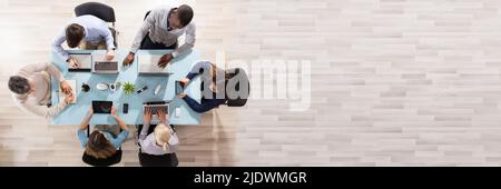 Elevated View Of Diverse Businesspeople Working On Desk Using Laptop And Digital Tablet Stock Photo