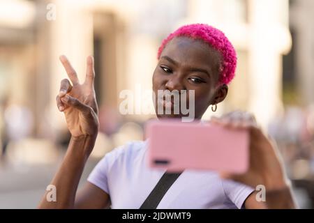 African woman gesturing victory with fingers while taking a selfie Stock Photo