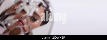 Reflection Of A Woman's Face In Broken Mirror Stock Photo