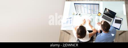Overhead View Of Two Businesspeople Analyzing Gantt Chart On Computer In Office Stock Photo