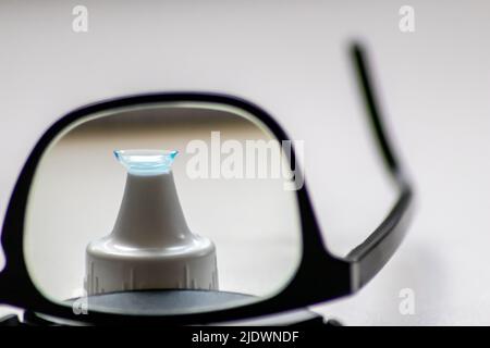 Blue contact lens through black eyeglasses shows different eyewear to correct farsightedness and nearsightedness by optometry or eye doctor myopia