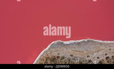 Flying over a pink salt lake. Salt production facilities saline evaporation pond fields in the salty lake. Dunaliella salina impart a red, pink water Stock Photo