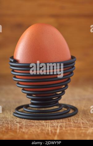 One boiled egg in a spiral-shaped metal support on wood background Stock Photo