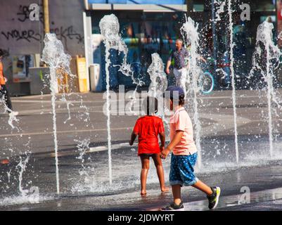 Vienna, Austria - 06.13.2022: Children frolic in the jets of the city fountain in the summer heat Stock Photo