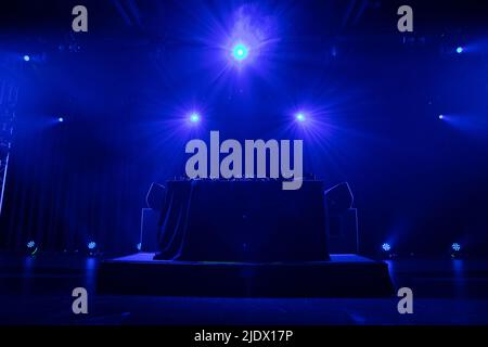 DJ booth set up on stage ready to be used with smoke and stage lighting Stock Photo