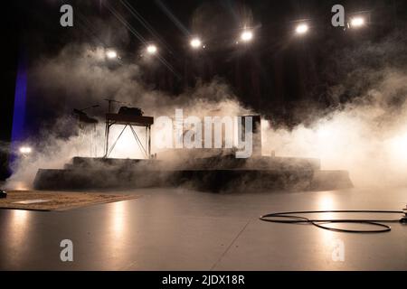 DJ booth set up on stage ready to be used with smoke and stage lighting Stock Photo