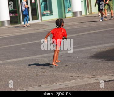 Vienna, Austria - 06.13.2022: Children frolic in the jets of the city fountain in the summer heat Stock Photo