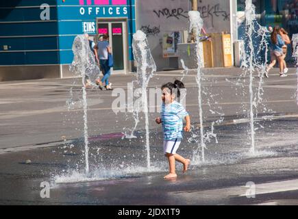 Vienna, Austria - 06.13.2022: Children frolic in the jets of the city fountain in the summer heat Stock Photo