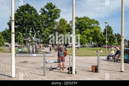 Young busker playing guitar in front of the Swan Fountain in Stratford upon Avon, Warwickshire, UK on 16 June 2022 Stock Photo