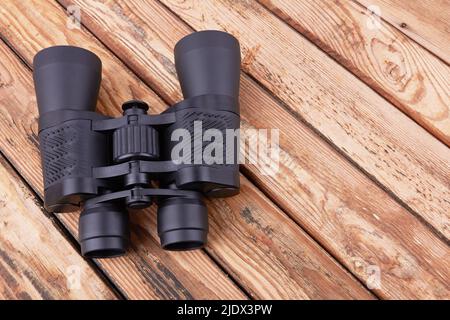 Black binoculars on a wooden surface Stock Photo