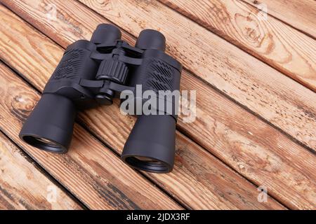 Black binocular on a wooden surface Stock Photo