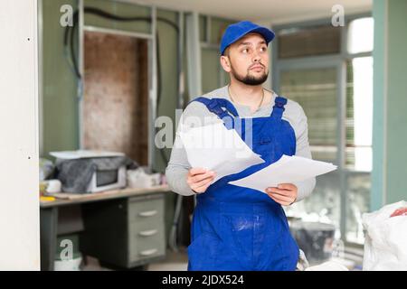 Foreman reading papers on indoor construction site Stock Photo