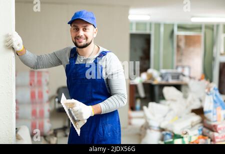 Positive man plasterer posing at renovating object Stock Photo