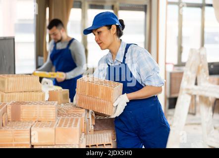 Repairman carrying bricks in construction site Stock Photo