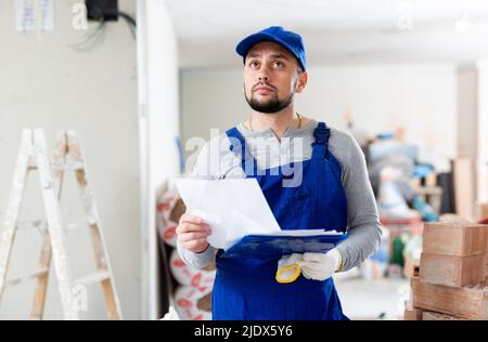 Foreman reading papers on indoor construction site Stock Photo