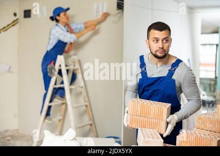 Man builder carrying bricks in construction site in apartment Stock Photo
