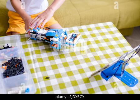 Kid collects robot from plastics details and programmed on tablet, robotics. Stock Photo