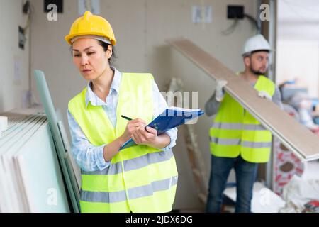 Female building inspector taking inventory of materials at construction site Stock Photo