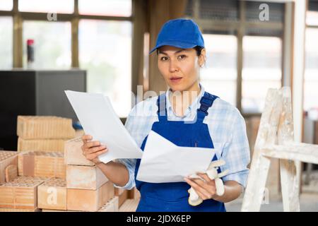 Woman making notes on indoor construction site Stock Photo