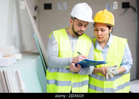 Two architects with papers discussing workflow at construction site Stock Photo