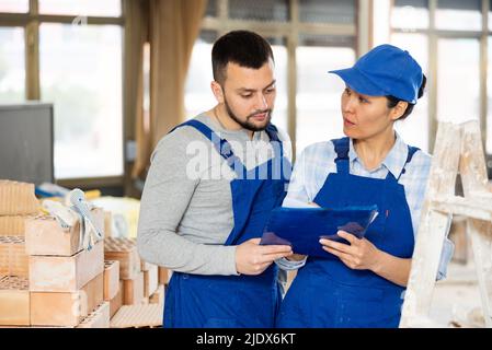 Man and woman builders discussing project documentation Stock Photo