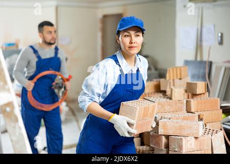 Repairman carrying bricks in construction site Stock Photo