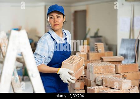 Female builder is laying bricks on top of each other Stock Photo