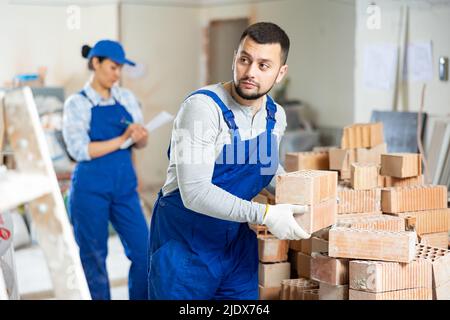 Builder carrying bricks while working in apartment Stock Photo