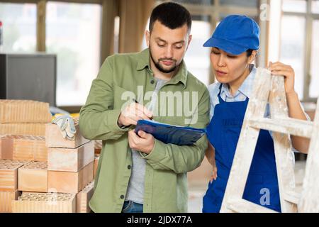 Woman repairer and man designer having conversation about documents Stock Photo