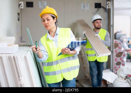 Female building inspector taking inventory of materials at construction site Stock Photo