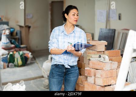 Woman making notes at renovating house Stock Photo