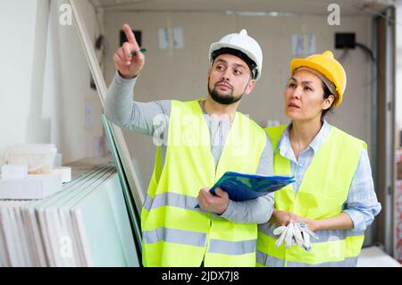 Two architects with papers discussing workflow at construction site Stock Photo