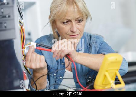 senior female technician using voltage meter Stock Photo