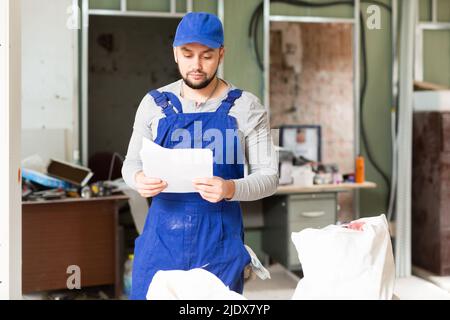 Foreman reading papers on indoor construction site Stock Photo