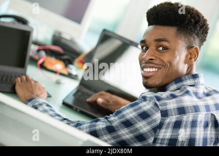 portrait of a male computer engineer using two laptops Stock Photo